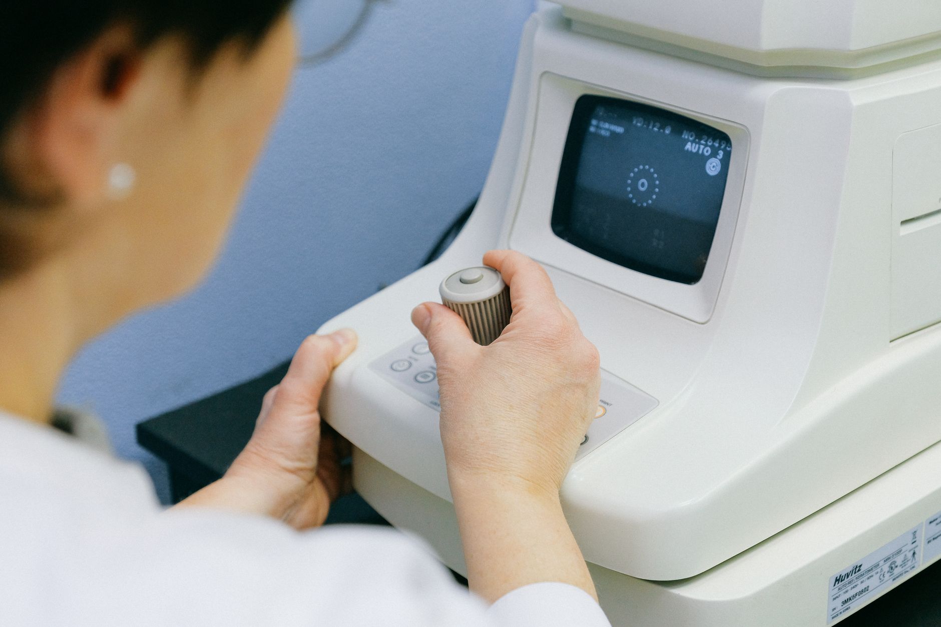 A clinical staff member positioning a patient at a tabletop fundus camera